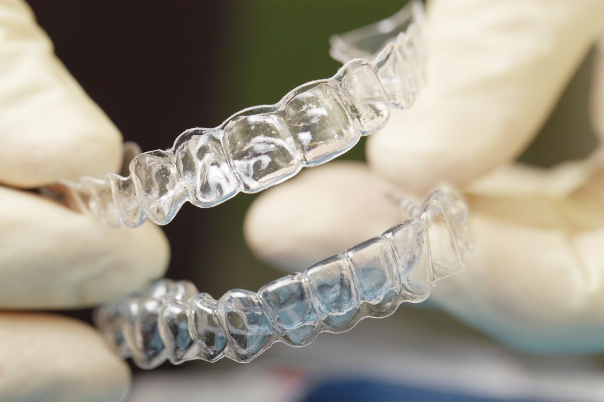 Gloved hands holding a clear orthodontic retainer